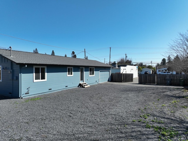 view of front facade featuring fence, entry steps, roof with shingles, crawl space, and driveway