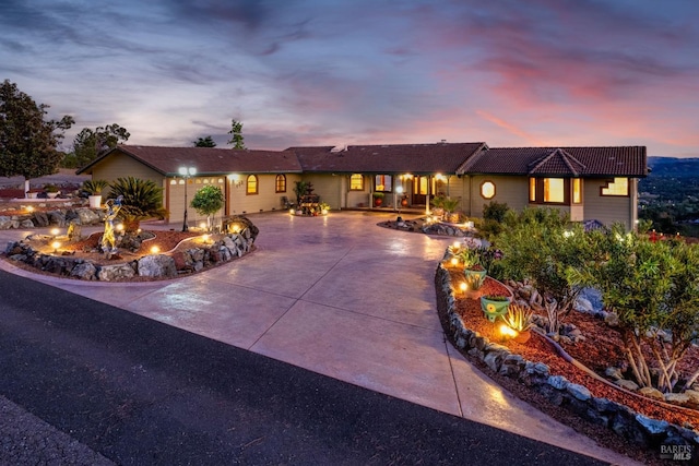 ranch-style home with an outdoor fire pit, a tile roof, and concrete driveway