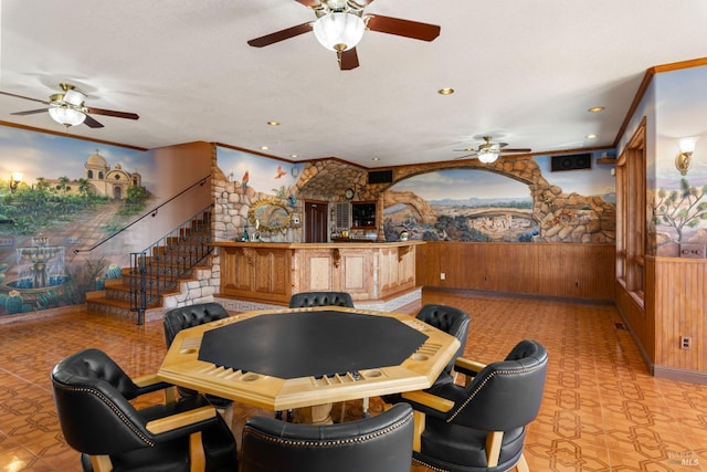 game room with a wainscoted wall, crown molding, and wood walls