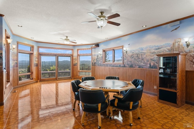 dining space with a healthy amount of sunlight, a wainscoted wall, and a textured ceiling