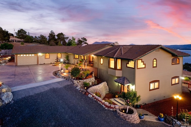 view of front of property featuring a tile roof, driveway, a chimney, and an attached garage