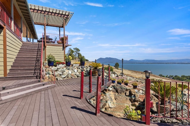 deck with a water and mountain view, stairway, and a pergola