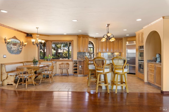 kitchen with light wood-style flooring, appliances with stainless steel finishes, decorative backsplash, and crown molding