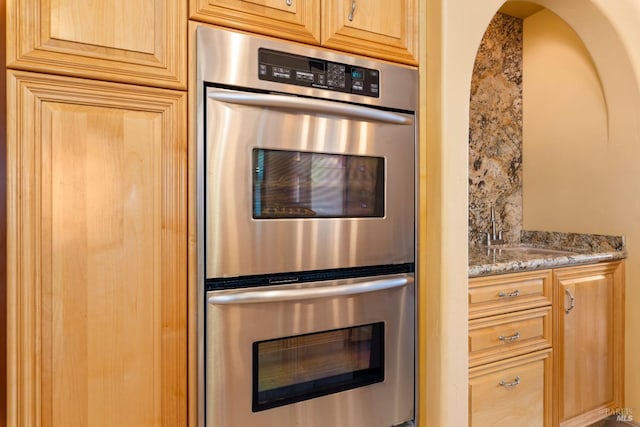 kitchen with stainless steel double oven and light stone countertops