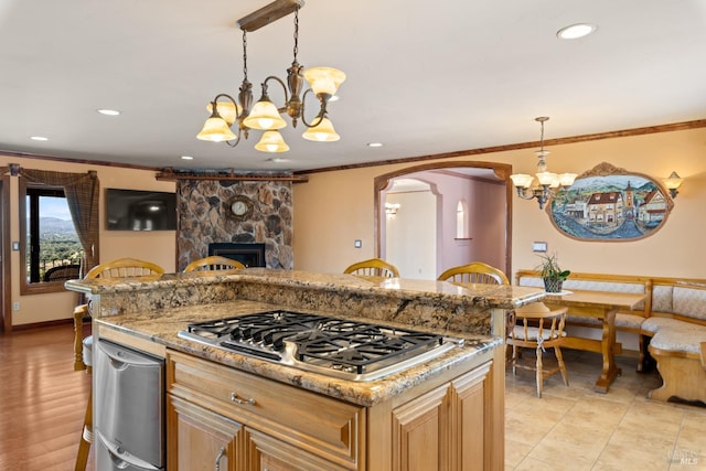 kitchen with arched walkways, a notable chandelier, stainless steel gas cooktop, a fireplace, and ornamental molding