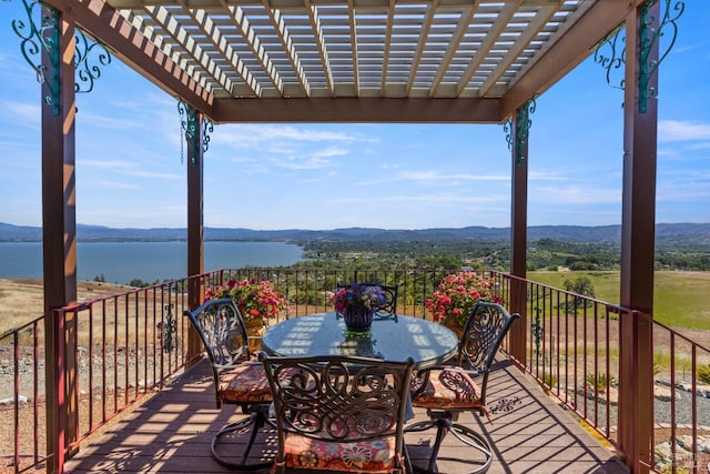 wooden terrace with outdoor dining space, a water and mountain view, and a pergola