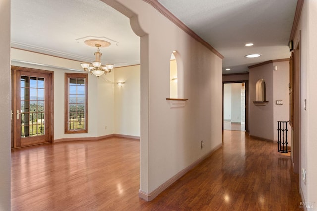 hallway featuring a chandelier, recessed lighting, wood finished floors, baseboards, and crown molding