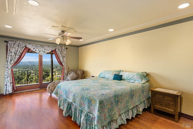 bedroom with crown molding, ceiling fan, a mountain view, a textured ceiling, and wood finished floors