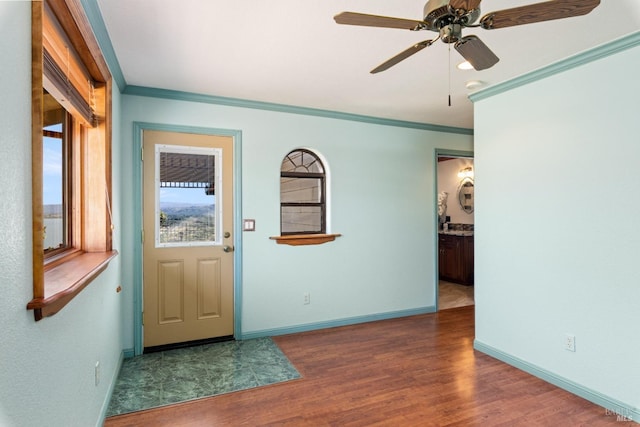 interior space with ornamental molding, ceiling fan, baseboards, and wood finished floors