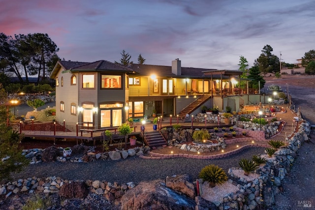 back of property featuring a chimney, a wooden deck, and stairs