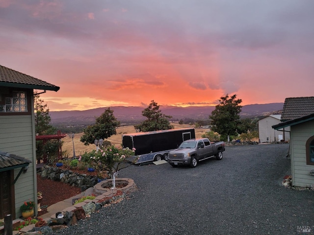 yard at dusk with gravel driveway and a mountain view