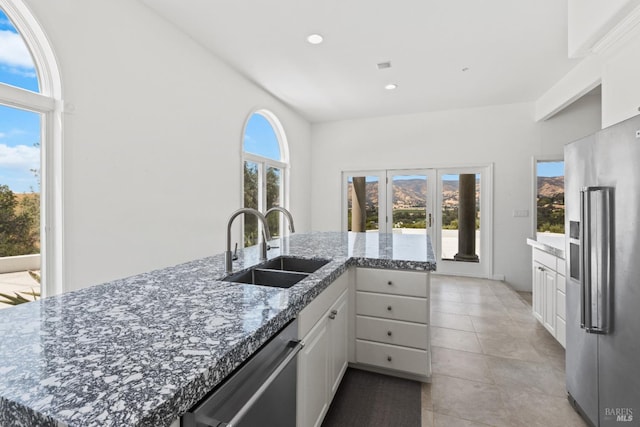 kitchen featuring stainless steel appliances, a healthy amount of sunlight, white cabinets, and a sink