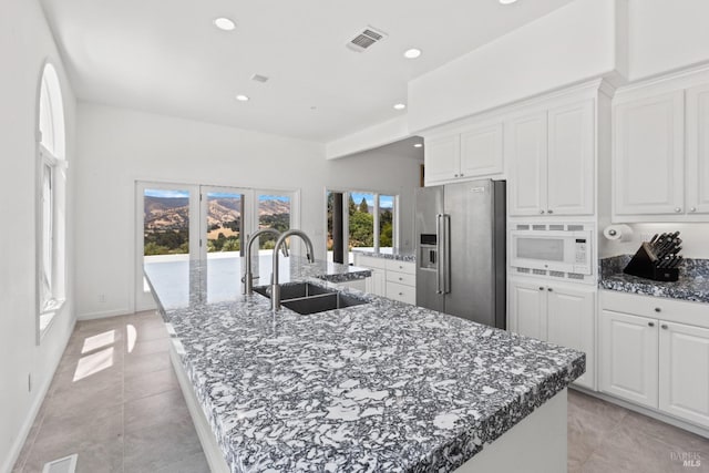 kitchen with a spacious island, high end fridge, visible vents, white microwave, and a sink