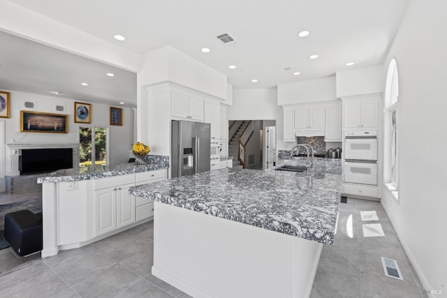 kitchen featuring high quality fridge, visible vents, a sink, and white double oven