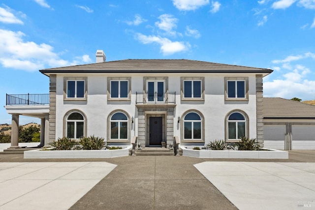 view of front of home with a garage, a chimney, a balcony, and concrete driveway