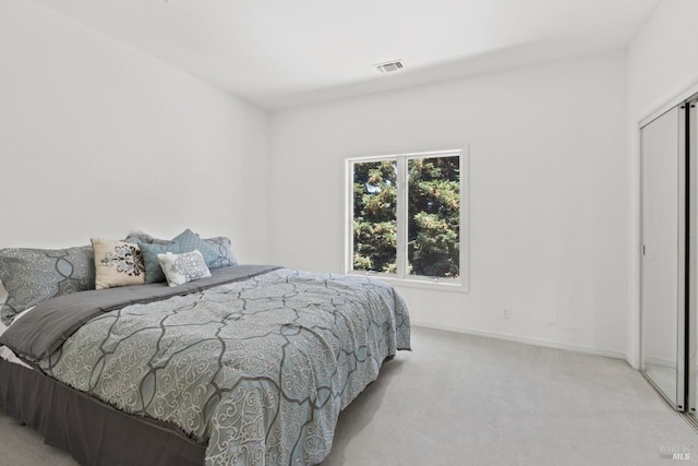 carpeted bedroom with a closet, visible vents, and baseboards