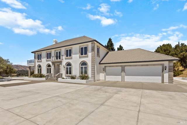 view of front of property with a chimney, concrete driveway, a balcony, and an attached garage