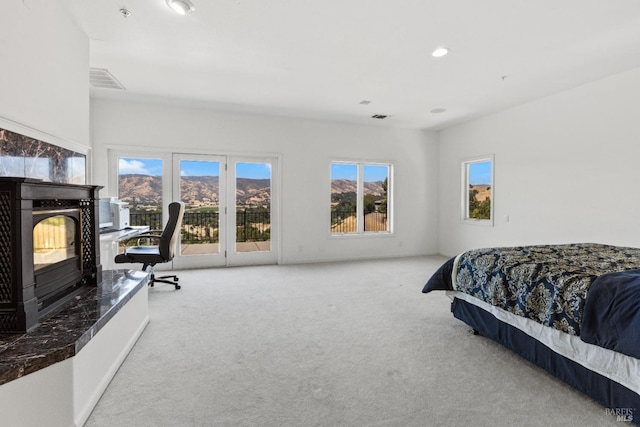 bedroom with visible vents, a high end fireplace, carpet flooring, a mountain view, and access to outside