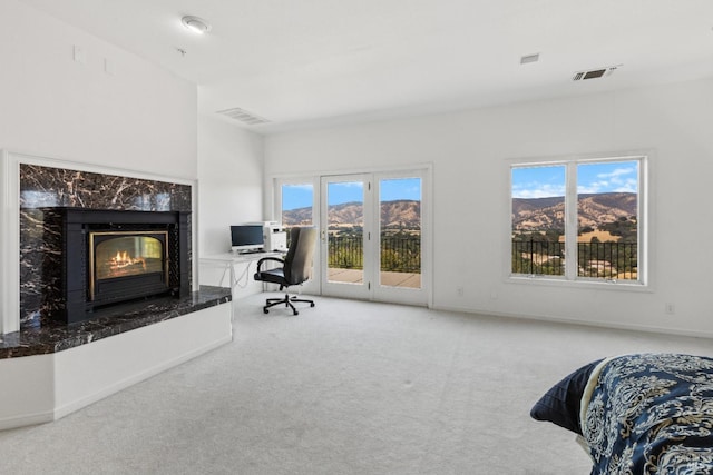 interior space with carpet floors, a premium fireplace, visible vents, and baseboards