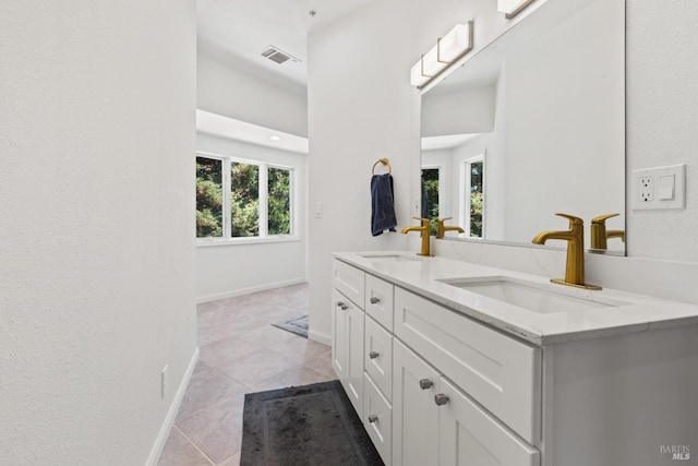 full bathroom with double vanity, baseboards, visible vents, and a sink