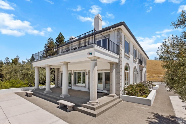 rear view of house featuring a balcony and a chimney