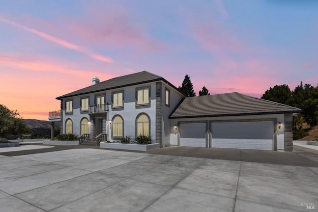 view of front of home with a garage, concrete driveway, and a balcony