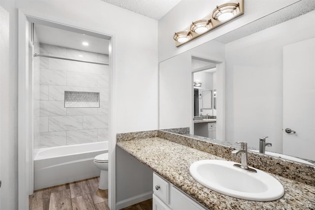 bathroom featuring toilet, wood finished floors, bathtub / shower combination, a textured ceiling, and vanity