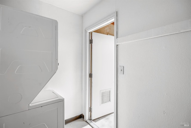 clothes washing area featuring stacked washer / dryer, electric panel, and visible vents