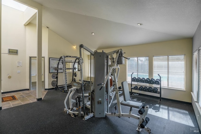 gym with lofted ceiling, a textured ceiling, and baseboards