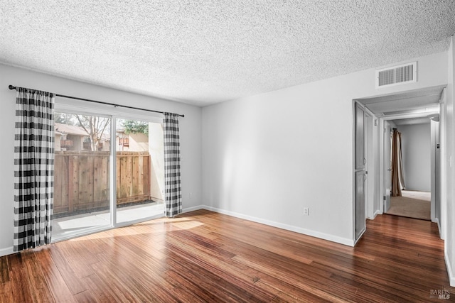 spare room featuring visible vents, a textured ceiling, baseboards, and wood finished floors