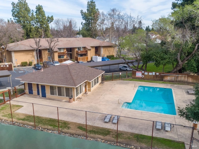 community pool with a patio area, fence, and a sunroom