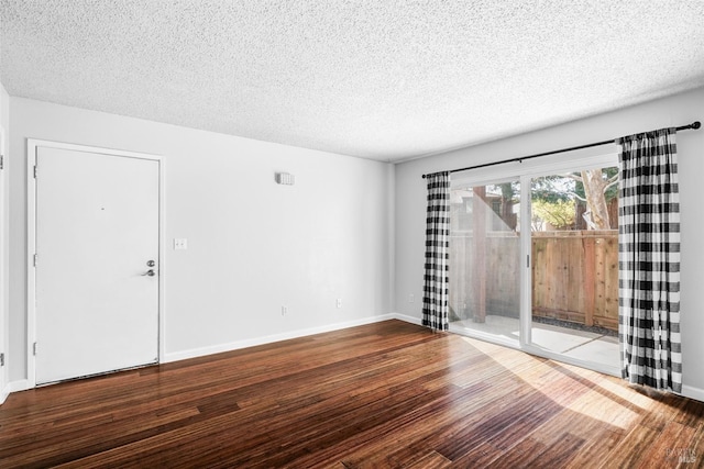 spare room featuring a textured ceiling, baseboards, and wood finished floors