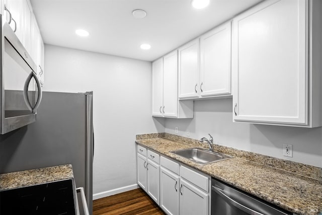 kitchen featuring stainless steel appliances, a sink, white cabinetry, baseboards, and dark wood-style floors