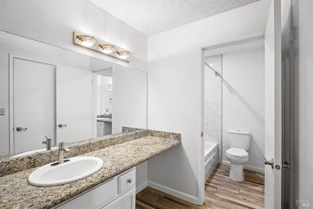 full bath featuring baseboards, toilet, wood finished floors, a textured ceiling, and vanity