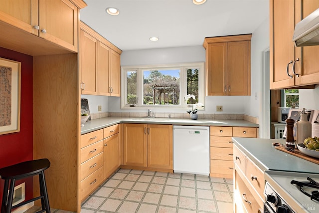 kitchen featuring gas range oven, white dishwasher, light countertops, under cabinet range hood, and recessed lighting