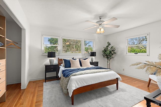 bedroom featuring light wood-style flooring, baseboards, and a ceiling fan