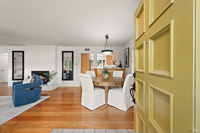 dining room with a large fireplace, visible vents, and light wood-style floors