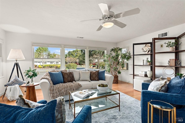 living room featuring ceiling fan, a textured ceiling, visible vents, and light wood-style floors