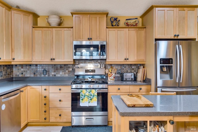 kitchen featuring stainless steel appliances, dark countertops, and light brown cabinets