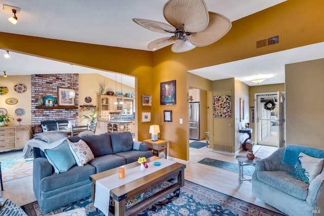 living area featuring visible vents, a ceiling fan, vaulted ceiling, wood finished floors, and baseboards