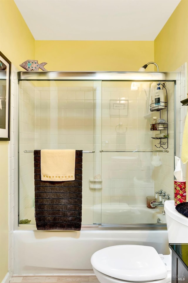 bathroom with bath / shower combo with glass door, vanity, and toilet