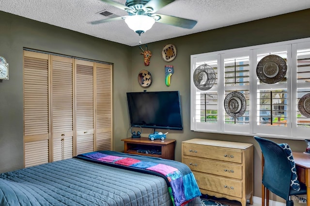 bedroom with a closet, visible vents, ceiling fan, and a textured ceiling