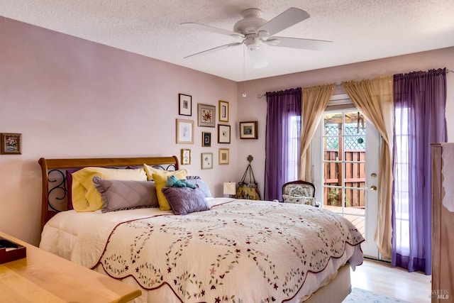 bedroom featuring a textured ceiling, access to outside, ceiling fan, and wood finished floors