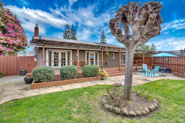 back of property with a lawn, a patio, a chimney, fence, and stucco siding