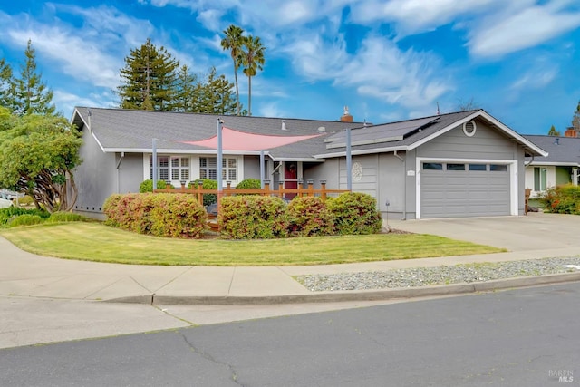 ranch-style house with a front yard, roof mounted solar panels, driveway, and an attached garage