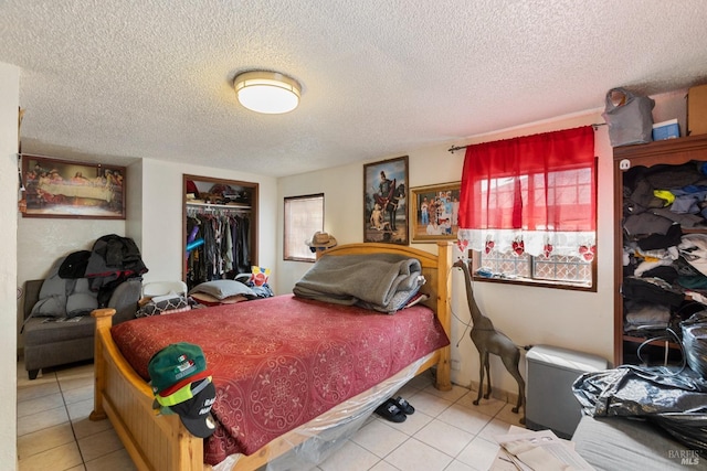 bedroom featuring a textured ceiling, multiple windows, a closet, and tile patterned flooring