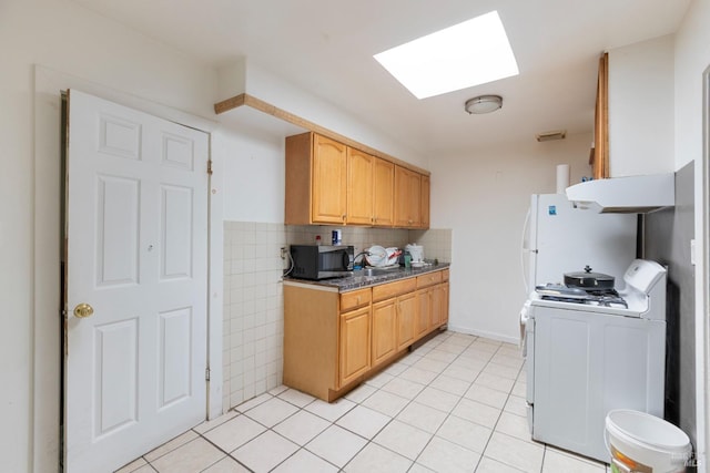 kitchen with light tile patterned floors, white appliances, extractor fan, and a skylight