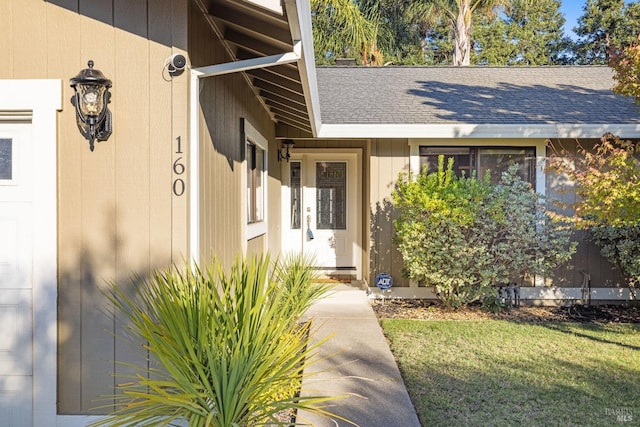 doorway to property featuring a lawn and roof with shingles