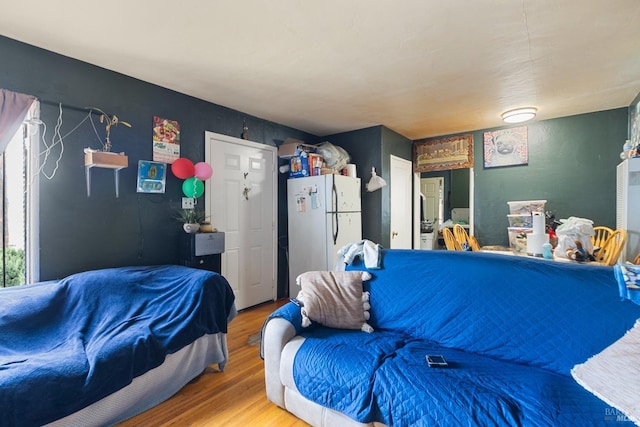 bedroom featuring wood finished floors and freestanding refrigerator