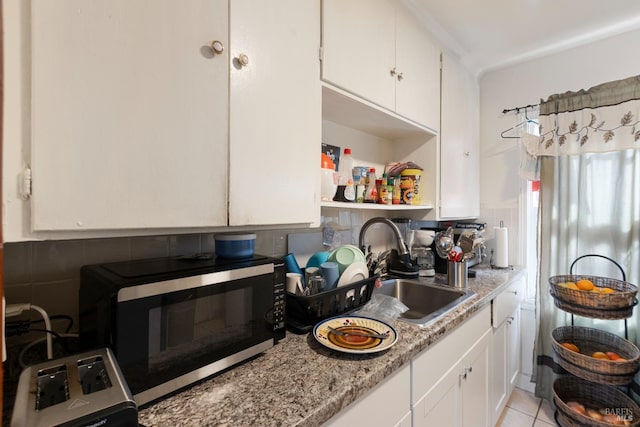 kitchen with light tile patterned floors, a sink, white cabinetry, open shelves, and backsplash